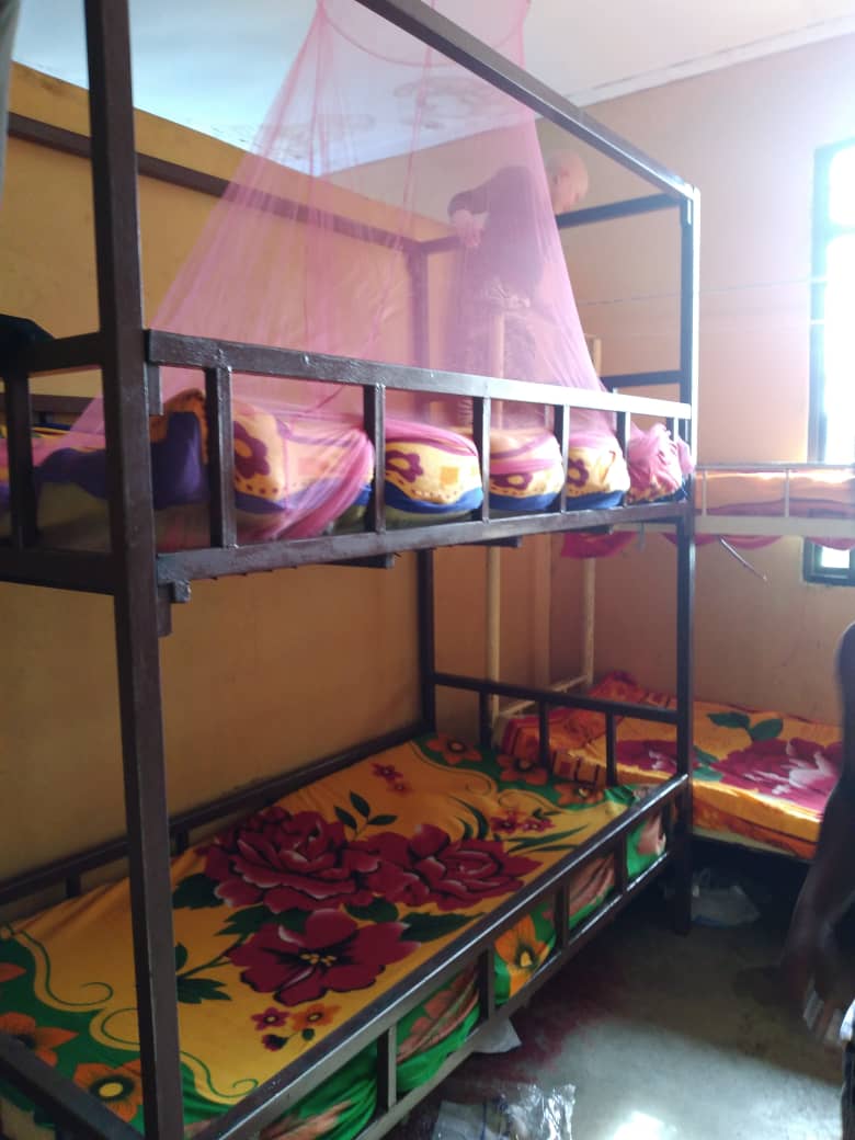 Bunk beds with floral bedding and pink mosquito netting in a dormitory
